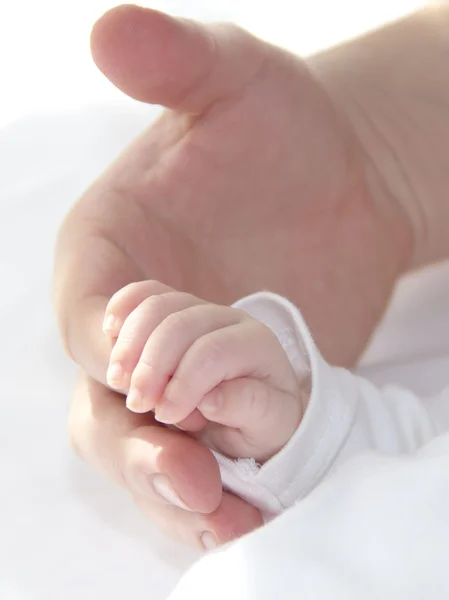Tiny hand van baby houdt vaders hand Stockfoto