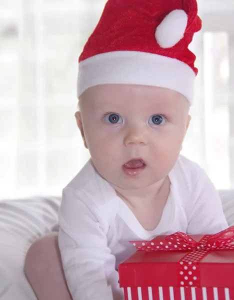 Cute baby in red new year hat with present — Stock Photo, Image