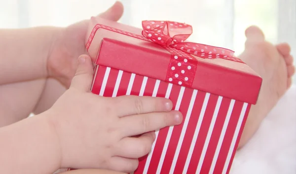 Petit enfant tient et ouvre la boîte cadeau rouge Photos De Stock Libres De Droits