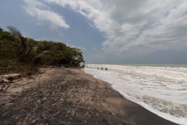 Bulutlu gökyüzü ve siyah kumla kaplı Palomino sahili 