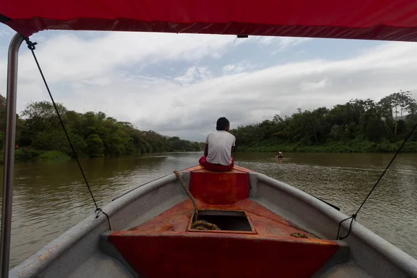 Güneşli bir günde arka planda Sierra Nevada dağları olan Palomino Nehri manzaralı bir teknede oturan bir çocuk.