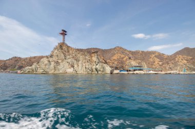 Akvaryumun yakınındaki beyaz sahil manzaralı tepeler bir turist teknesinden izleniyor.