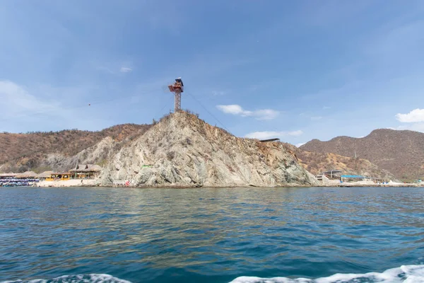 Kolombiya Santa Marta Playa Blanca ya da beyaz plaj kıyıları dağın tepesinde tepe örtüsü ada kulesi ve mavi deniz.