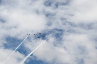 Super Tucano airplanes flying in V formation with blue cloudy sky at background