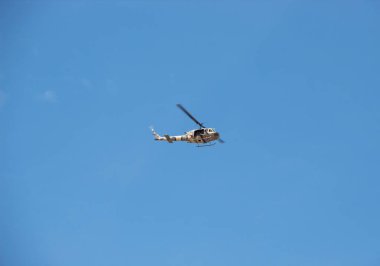 Yellow and green army helicopter flying with blue sky at background