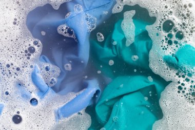 Renkli giysiler toz deterjana batırılmış su çözeltisi. Çamaşır konsepti