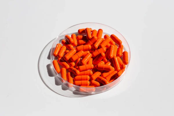 白を背景にペトリ皿のオレンジカプセル薬 — ストック写真