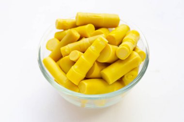 Beyaz arka planda cam kasede korunmuş bambu filizi..