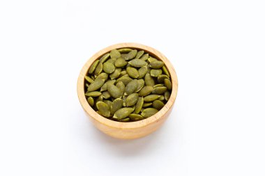 Beyaz arka planda tahta kasede kabak tohumları.