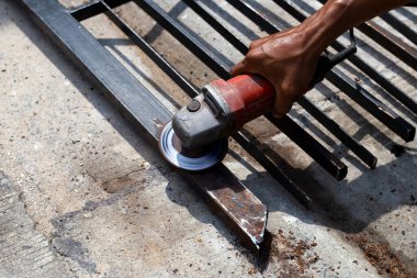 Yaklaş, üçkağıtçıyla çalışan bir adam. Demir kapı onarımı