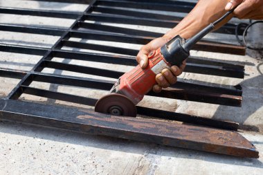 Yaklaş, üçkağıtçıyla çalışan bir adam. Demir kapı onarımı