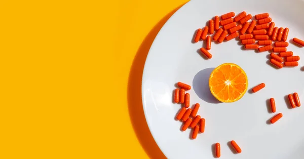 オレンジの背景に白いプレートにカプセル薬とオレンジの果実 — ストック写真