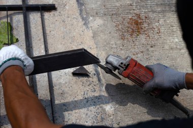 Yaklaş, üçkağıtçıyla çalışan bir adam. Demir kapı onarımı