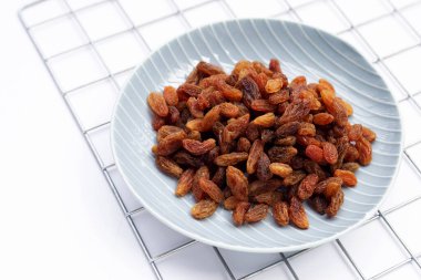 Beyaz arka planda kuru üzüm tabağında.
