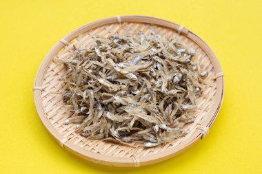 Sarı arka planda bambu sepetinde kurutulmuş ançüez..