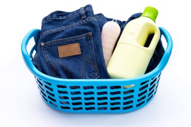 Beyaz arka planda çamaşır sepetinde mavi kot pantolon.