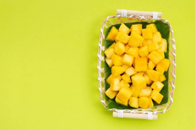 Tropik meyve, yeşil arka planda bambu sepetinde mango küp dilimleri..