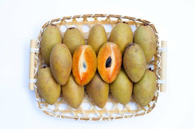 Bambu sepetinde beyaz arka planda taze sapodilla meyvesi.