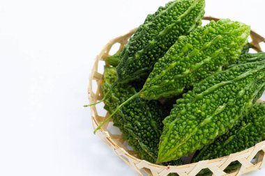 Beyaz arka planda bambu sepetinde acı kabak..