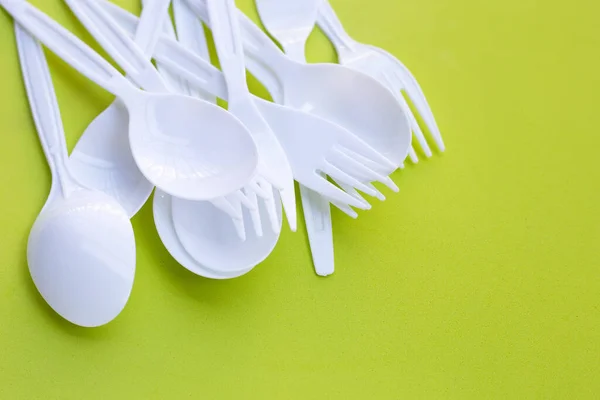 绿色背景的塑料叉子和勺子 — 图库照片