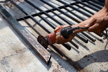 Yaklaş, üçkağıtçıyla çalışan bir adam. Demir kapı onarımı