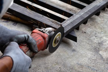 Yaklaş, üçkağıtçıyla çalışan bir adam. Demir kapı onarımı