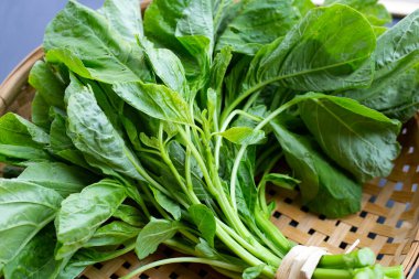 Siyah arka planda, bambu sepetinde yeşil ıspanak.