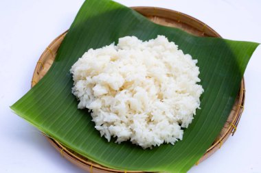 Muz yaprağına yapış yapış pirinç, beyaz arka planda bambu sepeti..