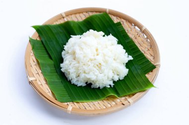 Muz yaprağına yapış yapış pirinç, beyaz arka planda bambu sepeti..