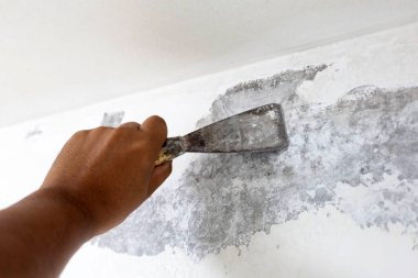 İşçi eli eski boyaları kazıyor.