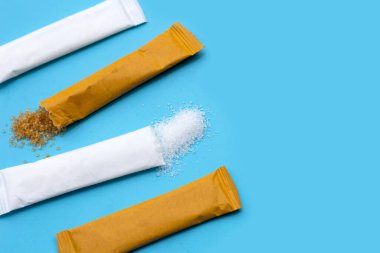 Mavi arkaplanda beyaz ve kahverengi şeker kesesi.