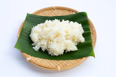 Muz yaprağına yapış yapış pirinç beyaz arka planda bambu dokuma tabağıyla.