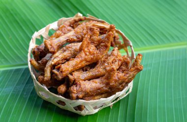 Kızarmış tavuk ayağı muz yaprağında bambu sepetinde.