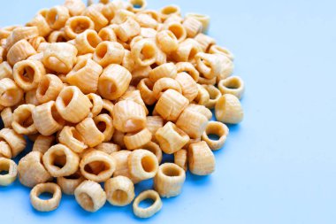 Mavi arka planda gevrek patates halkaları.