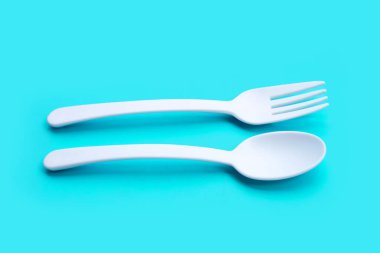 Mavi arka planda plastik çatal ve kaşık.