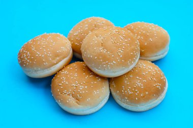 Mavi arka planda susamlı hamburger çörekleri..