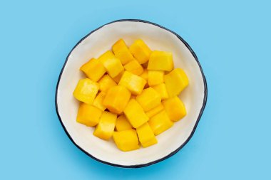 Tropikal meyve, mango küp dilimleri mavi arka planda kasede.