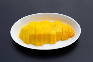 Koyu arkaplanda sarı mango dilimleri.