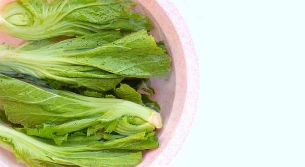 Mustard Green soaked in a pink bowl of water. Wash vegetables