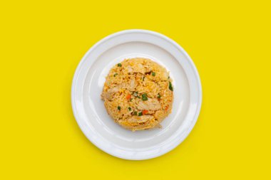 Sarı arka planda beyaz tabakta kızarmış pirinç..