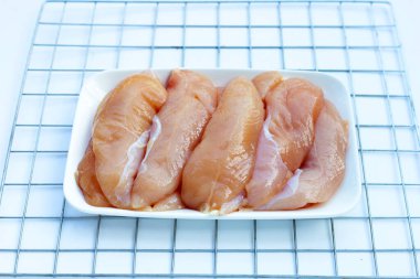 Beyaz arka planda çiğ tavuk ihaleleri.