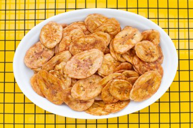 Banana chips on yellow background.