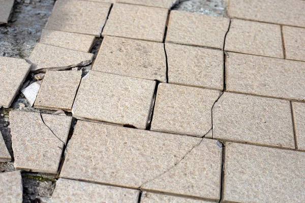 Cracked brown tiles on cement floor