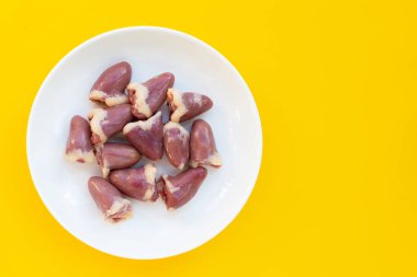 Sarı arka planda beyaz tabakta taze çiğ tavuk kalbi..