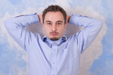 Ellerini başının üstüne koy olan genç adam