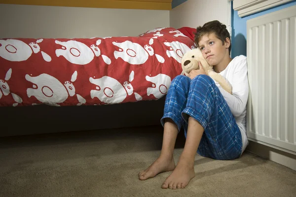 Грустный и подавленный мальчик в спальне — стоковое фото