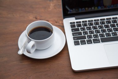 bir tablo ile bir bilgisayar üzerinde beyaz bir fincan sade kahve.