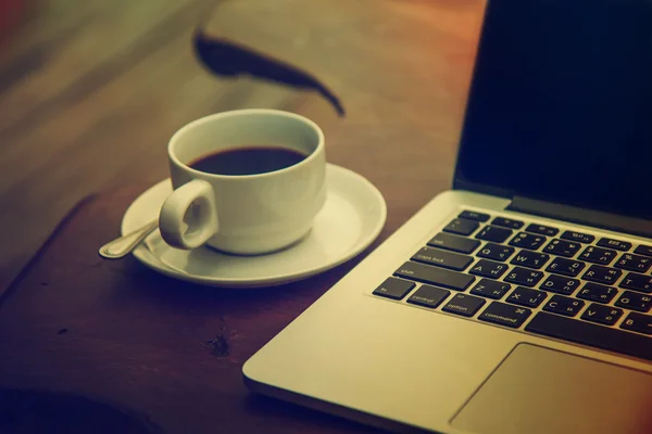 Café negro en una taza blanca en una mesa con un ordenador . — Foto de Stock