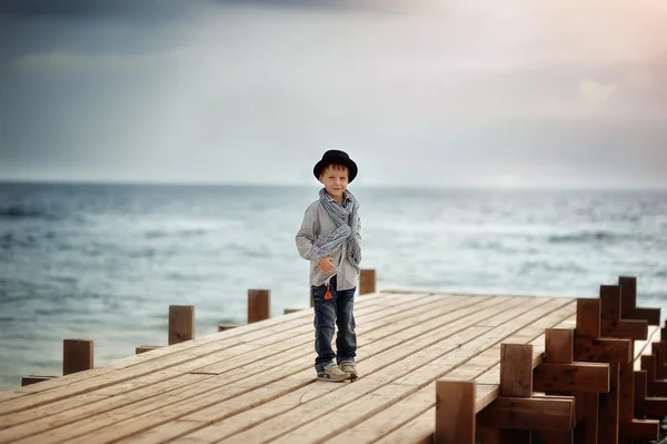 Мальчик на мосту у моря — стоковое фото