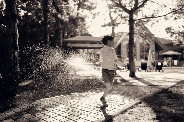 Um menino e um spray de água — Fotografia de Stock